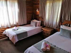a hotel room with two beds with towels on them at Eight Bells Mountain Inn in Ruiterbos