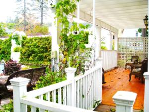 um alpendre branco com uma cerca branca e plantas em The White House Inn em Cooperstown