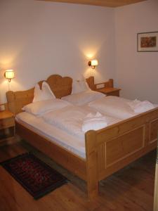 Un dormitorio con una gran cama de madera con sábanas blancas. en Residence Rosarela, en Badia