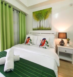 a bedroom with a large white bed with green curtains at An Oasis in Tagaytay in Tagaytay