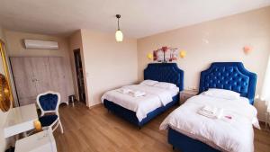 SokakagziにあるAssos Nazan Motel Restoran Beachのベッドルーム1室(青いヘッドボード付きのベッド2台付)