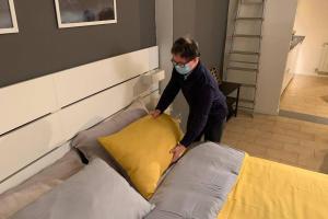 mężczyzna w masce twarzy robiący łóżko w obiekcie Appartamento Via delle Idee w Bolonii