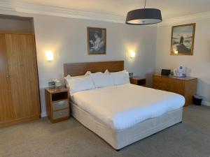 a hotel room with a bed, desk and a lamp at Legends Hotel in Brighton & Hove