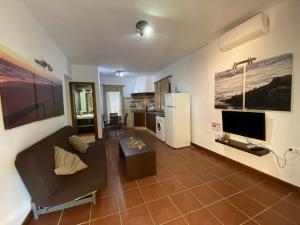 a living room with a couch and a tv at Casa con jardín privado y piscina compartida in Cádiz