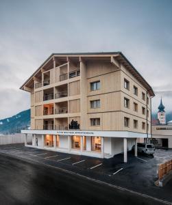 a large building in a parking lot next to a building at das bleibt Alpine Suites in Schladming