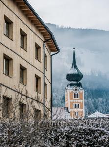 a building with a clock tower next to a building at das bleibt Alpine Suites in Schladming