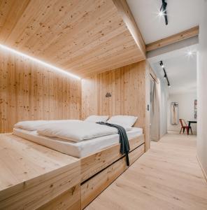 una camera con un letto su una parete in legno di das bleibt Alpine Suites a Schladming