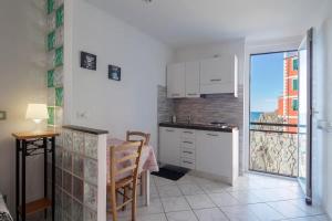 a kitchen with white cabinets and a table and a balcony at Giovanna dei Rocca - appartamento sul mare in Riomaggiore +12 photos