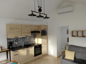 eine Küche mit Holzschränken und ein Sofa im Zimmer in der Unterkunft Petite Maison refaite à neuf proche plage in Mèze