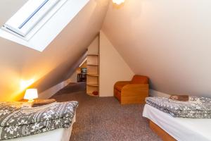 a attic bedroom with two beds and a chair at Gospoda i Noclegi Na szlaku in Kudowa-Zdrój