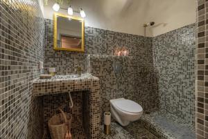 a bathroom with a toilet and a sink and a mirror at BLACK BAY CAVES SUITES in Akrotiri +30 photos