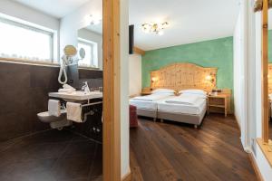 - une chambre avec un lit, un lavabo et un miroir dans l'établissement Hotel Foresta, à Moena