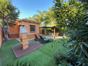 une arrière-cour avec un grill, une table et des chaises dans l'établissement Casa Bungalows con jardín privado y piscina compa, à Cadix