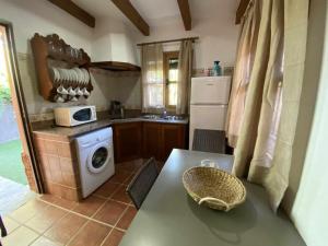une cuisine avec une table et une machine à laver dans l'établissement Casa Bungalows con jardín privado y piscina compa, à Cadix