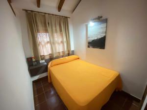 un lit jaune dans une chambre avec une fenêtre dans l'établissement Casa Bungalows con jardín privado y piscina compa, à Cadix 29 autres photos