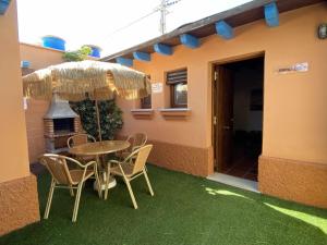 stół i krzesła pod parasolem na tarasie w obiekcie Estudio con jardincito privado barbacoa y piscina w Kadyksie