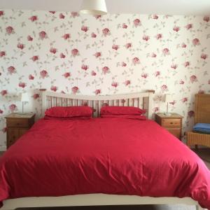 a bedroom with a red bed with flowers on the wall at Lovely 3-Bed Cottage Portmahomack next to harbour in Portmahomack