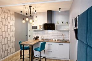 a kitchen with a table and two blue chairs at Allurapart Inn MVZ, Левобережная МВЦ in Kyiv