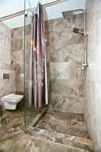 a shower with a glass door in a bathroom at Allurapart Inn MVZ, Левобережная МВЦ in Kyiv