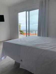 a white bed with a view of the ocean at Apartamentos de Juan in Morro de São Paulo