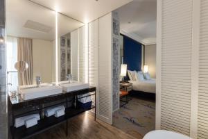 a bathroom with two sinks and a bed and a mirror at Pestana Plaza Mayor Madrid in Madrid