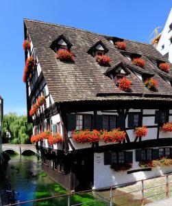 ein Gebäude mit Blumenkästen an den Fenstern neben einem Fluss in der Unterkunft Hotel Schiefes Haus in Ulm