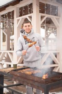 Ein Mann kocht Essen auf einem Grill in der Unterkunft Клуб відпочинку Dacha in Sokirno