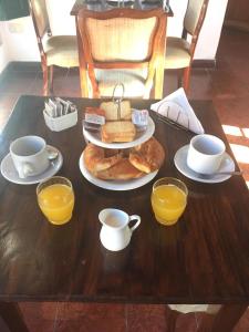 a table with a plate of food and cups of orange juice at Posta Torreón in Concepción del Uruguay