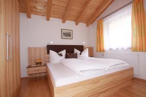 a bedroom with a large white bed with a wooden headboard at Apart Anna in Nauders