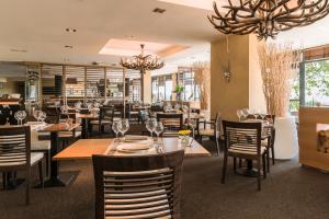 a restaurant with tables and chairs and a chandelier at Hôtel du Golf in Lumbres