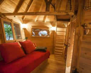 une petite chambre avec un canapé rouge dans une cabine dans l'établissement Parthénope - Les Cabanes du Chêne Rouvre, à Saint-Dié-des-Vosges