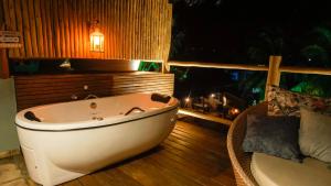 a bath tub sitting on a deck with a bed at Xamã Senses - Hotel Pousada in Pipa