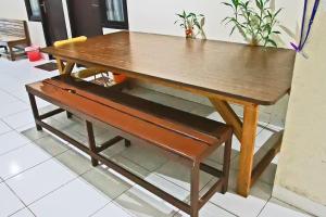una mesa de madera con un banco al lado en RedDoorz Plus at Pelita Guest House Balikpapan en Balikpapan