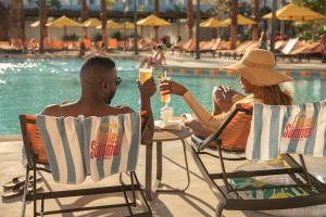 two people sitting at a table by a pool at Universal’s Endless Summer Resort – Dockside Inn and Suites in Orlando