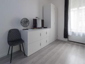 ein Wohnzimmer mit einem Stuhl und einem TV auf einer Kommode in der Unterkunft EXECUTIVE SINGLE ROOM WITH EN-SUITE in GUEST HOUSE CITY CENTRE in Luxemburg (Stadt)