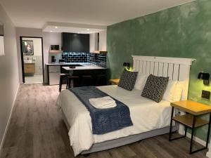 een slaapkamer met een groot bed en een keuken bij Coral Wood Self Catering Suites and B&B in East London