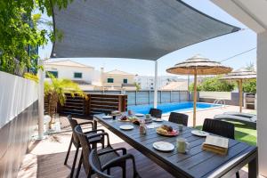un patio con mesa, sillas y piscina en CoolHouses Algarve, Casa Marisa, V5 Burgau, en Burgau