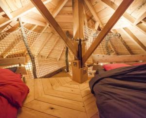 um quarto com uma rede de descanso num sótão de madeira em Gaïa - Les Cabanes du Chêne Rouvre em Saint-Dié-des-Vosges