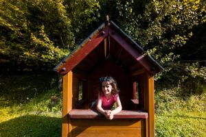 Una bambina seduta in una casetta per bambini di Relais Parco Fiorito & SPA - Agriturismo, Ristorante e Fattoria Didattica a Cortona