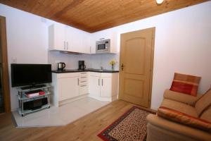 a living room with a television and a kitchen at Haus Scheglmann inkl. Chiemgaukarte in Ruhpolding