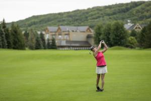 una mujer parada en un campo de golf sosteniendo un club en Blue Mountain Resort Village Suites, en Blue Mountains