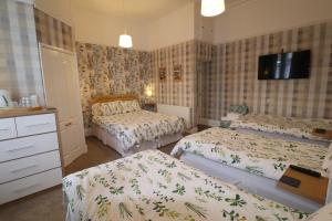 a bedroom with two beds and a tv on the wall at The Raincliffe Hotel in Scarborough
