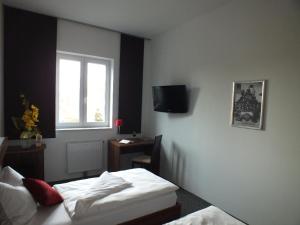 a bedroom with a bed and a desk and a window at Hotel Fabrik Vösendorf in Vösendorf