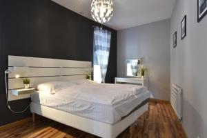 a bedroom with a large white bed and a chandelier at Apartament Flauta Pogorzelica in Pogorzelica