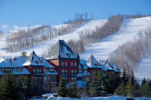 a large red building with snow covered roofs on a hill at Blue Mountain Resort Village Suites in Blue Mountains