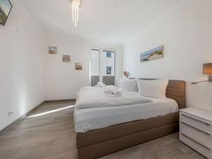 ein Schlafzimmer mit einem großen Bett mit weißer Bettwäsche in der Unterkunft Villa Vogue Wohnung Nr. 11 in Binz