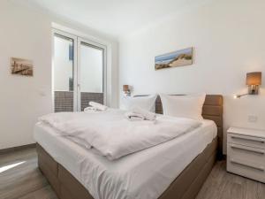 ein Schlafzimmer mit einem großen Bett mit weißer Bettwäsche in der Unterkunft Villa Vogue Wohnung Nr. 11 in Binz