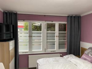 Habitación con ventanas, cama y TV. en Ferienzimmer Am Strom 34, en Rostock