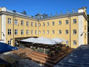 een groot geel gebouw met tafels en witte parasols bij Waterside Mariestad in Mariestad