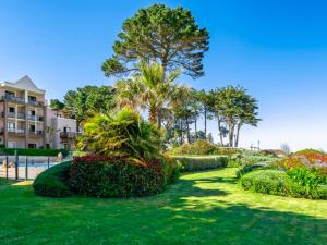 ein Park mit Büschen und Bäumen und ein Gebäude in der Unterkunft appartement vue mer 50m de la plage, WIFI gratuit in Perros-Guirec